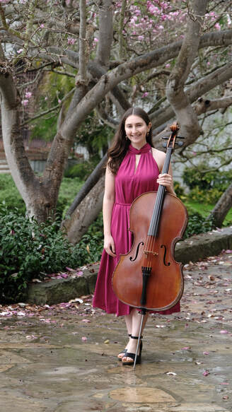 Picture of Kira Weiss standing with her cello in front of a tree